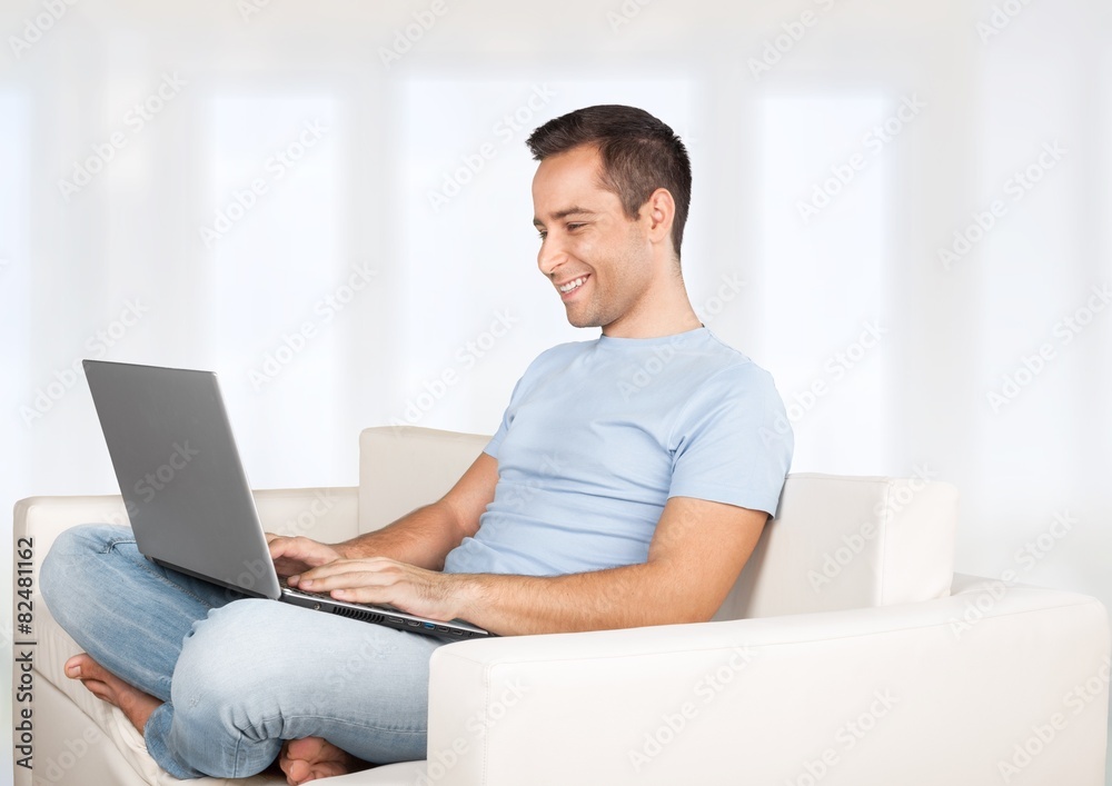 Wall mural laptop. happy smiling young man watching and working on computer