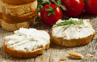 Home crostini with soft cheese and tomatoes on a wooden table, s