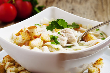 classic chicken noodle soup with crackers, selective focus