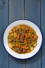 meat with vegetables in dish on blue background