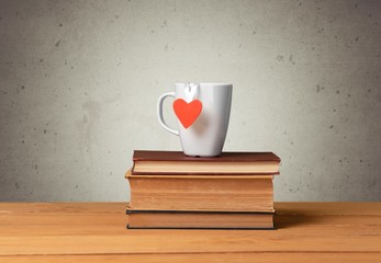 Backdrop. Coffee mug with heart shape on vintage books