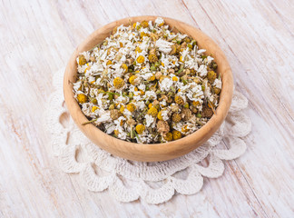 Dried camomile in wooden bowl