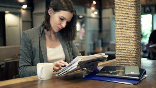 Young businesswoman reading newspaper while sitting in cafe
