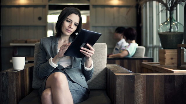 Businesswoman reading on tablet computer and drinking