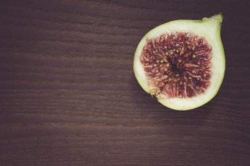 delicious half cut ripe fig on a dark wood surface - directly above view with copy space