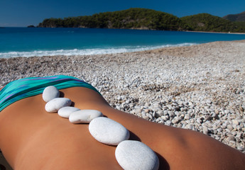Beautiful woman getting hot stones treatment out in the nature.