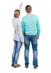 young couple pointing at wal Back view  (woman and man).