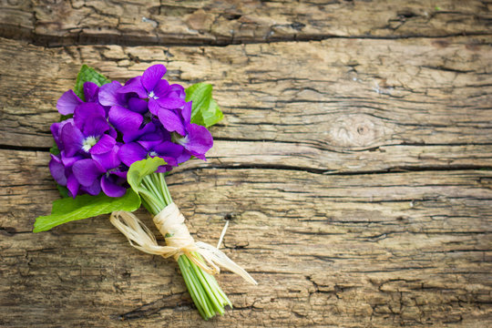 Beautiful bouquet of violets on the wooden background