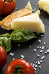 Italian Cheese on black stone background with basil and tomatoes