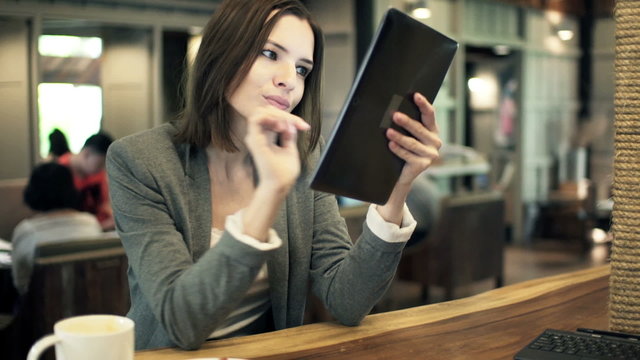 businesswoman with tablet eating croissant in cafe
