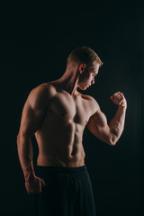 Fototapeta premium muscular young man showing his biceps isolated on black