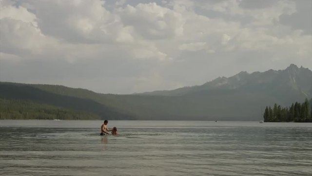Wide shot of young couple splashing in lake / Redfish Lake, Idaho, United States