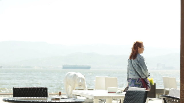 Girl walking the waterfront and sits down at in seaside cafe