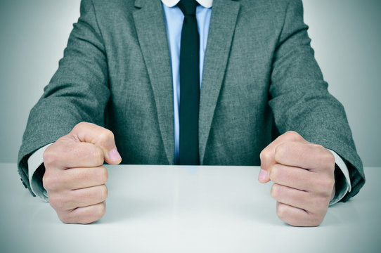 man in suit banging his fists on a desk