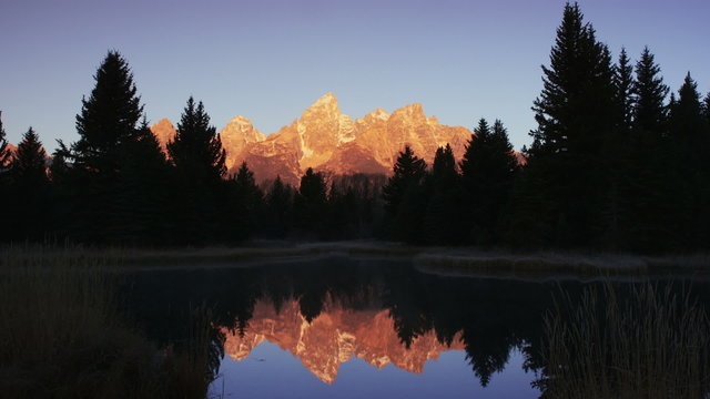 Wide shot of reflection of mountain and trees in river / Grand Teton National Park, Wyoming, United States