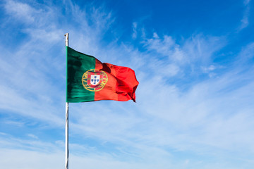 Portugal flag waving on the wind over a cloudy blue sky