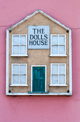 The Dolls house sign outside a terracotta cottage wall