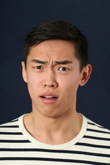 Disgusted young Asian man looking at camera