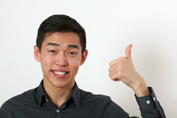 Smiling young Asian man giving the thumbs up signs and looking a