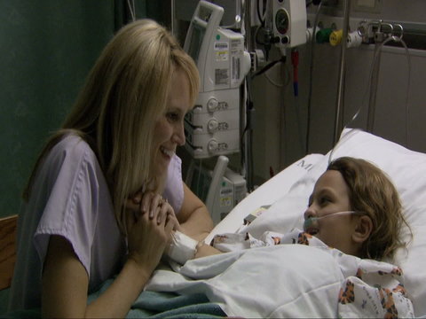 Nurse talking to and comforting child in hospital bed