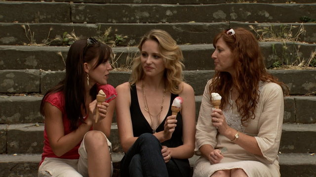 Three women eating ice cream on outdoor stairs