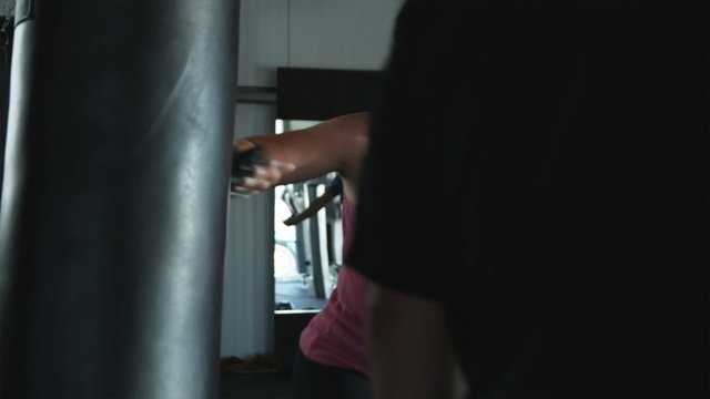 woman at the gym punching a heavy bag