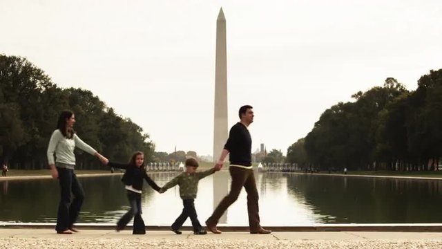 WS Family with two children (4-5, 6-7) walking along reflecting pool, Washington Monument in background, Washington D.C, USA