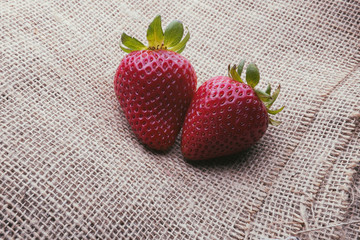Two strawberries on a burlap background