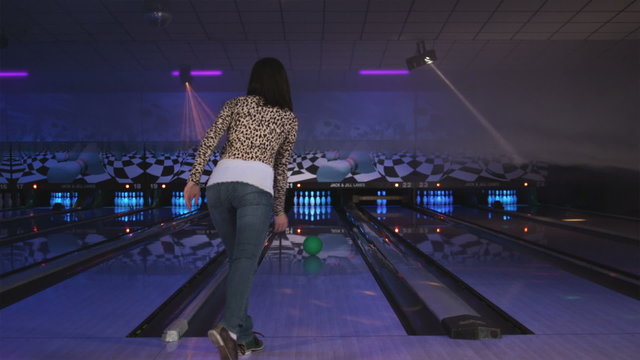 young woman at the bowling alley rolling a strike