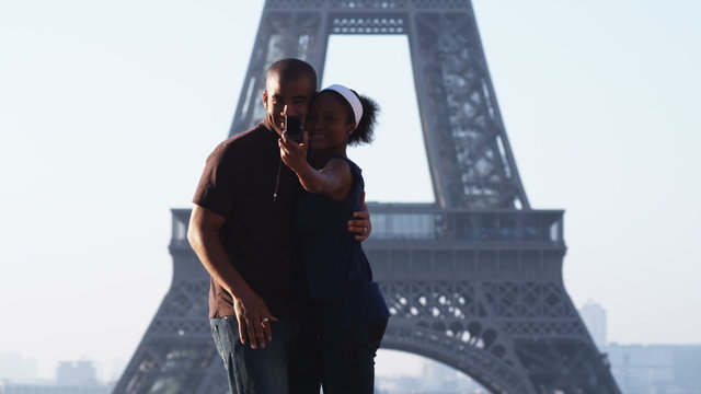 couple taking their own photo in front of the Eiffel tower