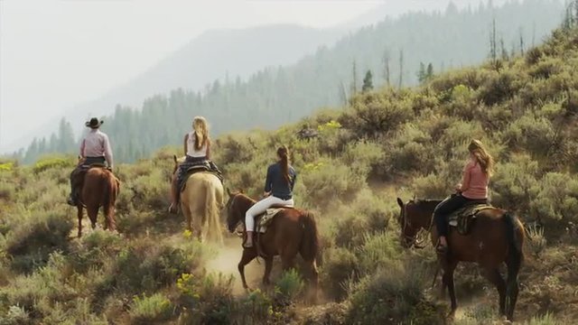 Panning medium shot of friends horseback riding / Idaho, United States