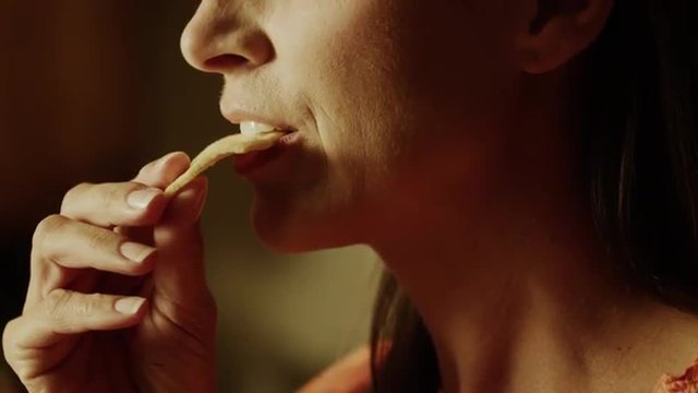 Slow motion close up panning shot of woman biting into pita chip / Cedar Hills, Utah, United States