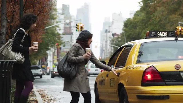 MS Two young women hailing and entering yellow cab, Manhattan, New York City, New York, USA