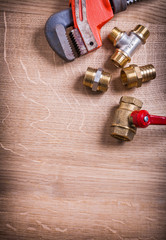 monkey wrench and brass plumbing fixtures  on wooden board with