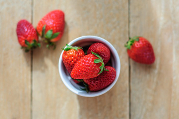 Strawberry in ceramic cup on wooden background