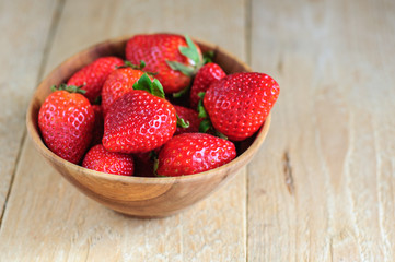Strawberry in wooden bowl on wooden background
