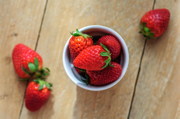 Strawberry in ceramic cup on wooden background