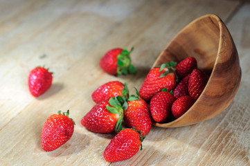 Strawberry spilling out from wooden bowl