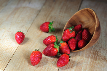 Strawberry spilling out from wooden bowl