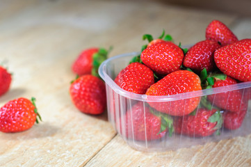 Strawberry in plastic box on wooden background