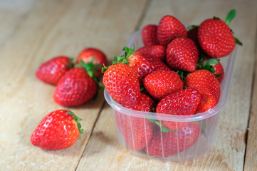 Strawberry in plastic box on wooden background