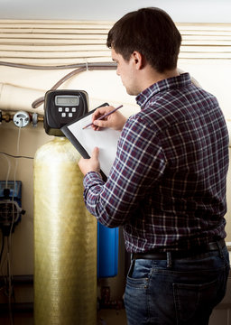 engineer writing down meter reading on industrial counters