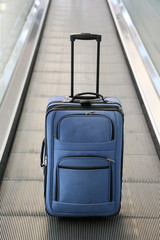 Blue suitcase on conveyor belt.
