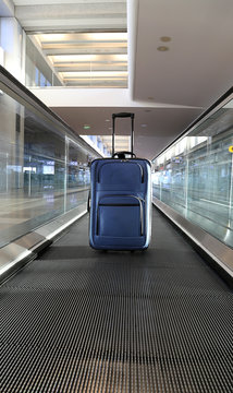 Blue suitcase on conveyor belt.