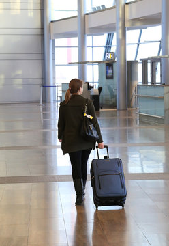 Young woman with blue suitcase at an airport