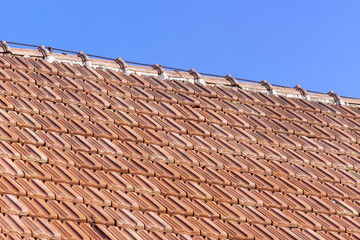 old roof of orange clay tiles with blue sky