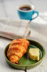 Breakfast with fresh baked croissants, butter and coffee, newspa