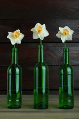 Daffodils in a bottle on a wooden background