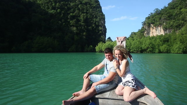 blonde girl and strong handsome guy sitting on longtail boat