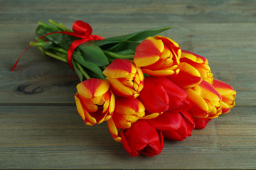 Bouquet of tulips with red ribbon on a wooden background